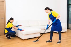 Cleaning staff performing deep home cleaning on sofa and floor